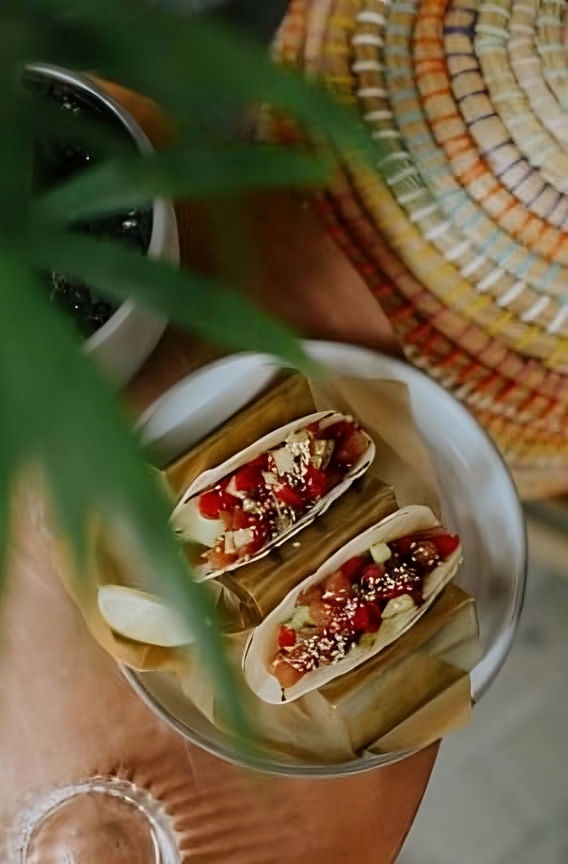 Two tacos on a plate with plant and basket